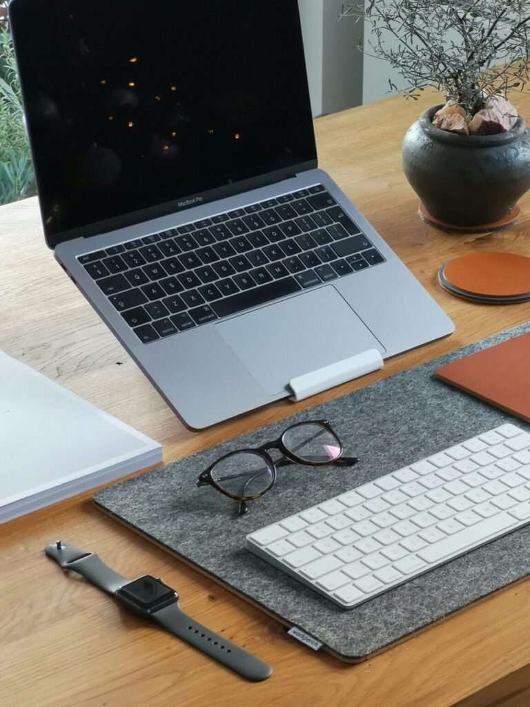 A small desk set up for better posture, laptop raised to eye level on a stand with an external keyboard - illustrating how to improve posture at a small desk