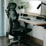Small desk setup with hidden cables, ergonomic mesh chair and a plant - a clean minimalist home office.