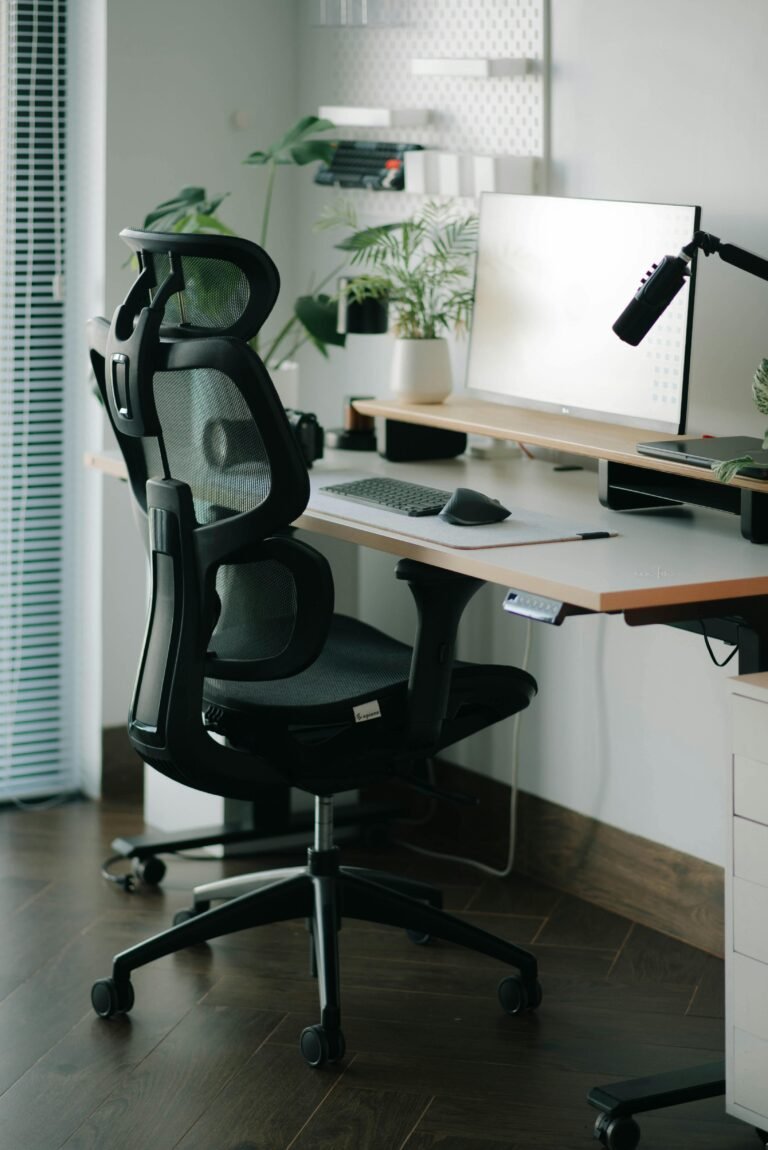 Small desk setup with hidden cables, ergonomic mesh chair and a plant - a clean minimalist home office.