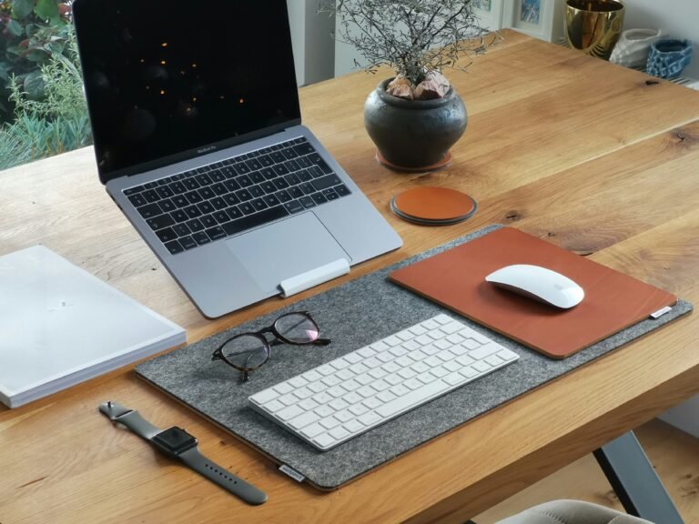 A small desk set up for better posture, laptop raised to eye level on a stand with an external keyboard - illustrating how to improve posture at a small desk